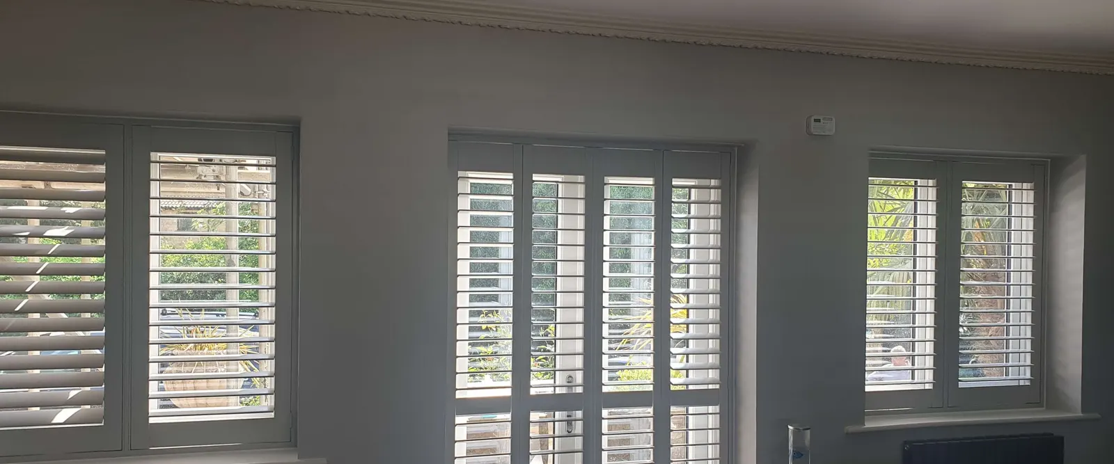 Georgia shutters fitted on two tall windows in a grey living room