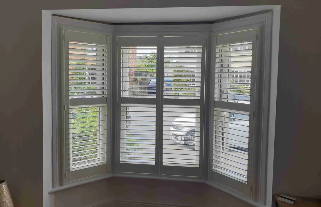 White shutters fitted to each face of an angled bay window
