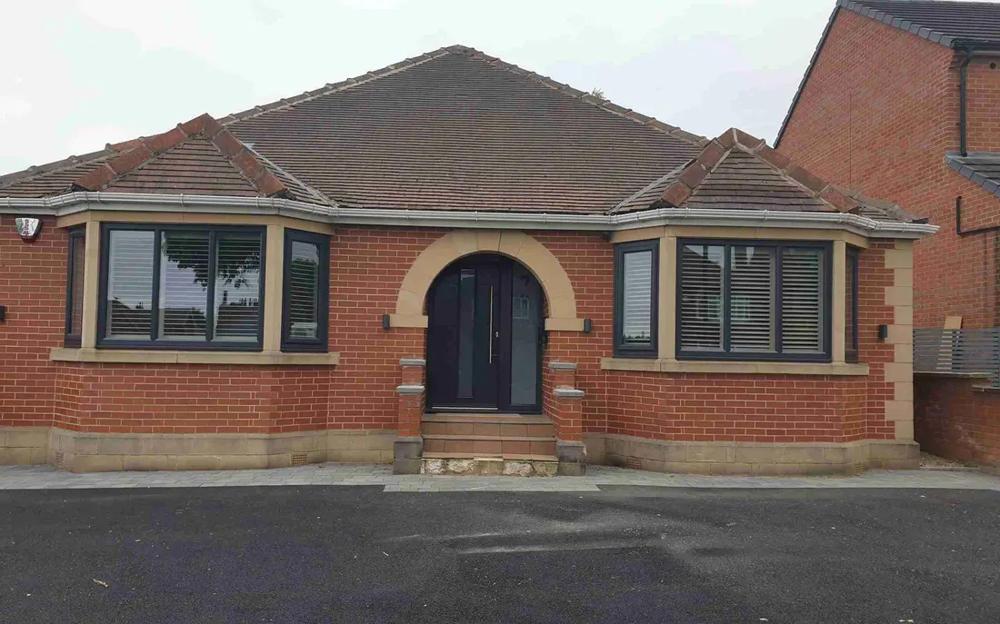 A brick bungalow from outside with shutters in its angled bay windows