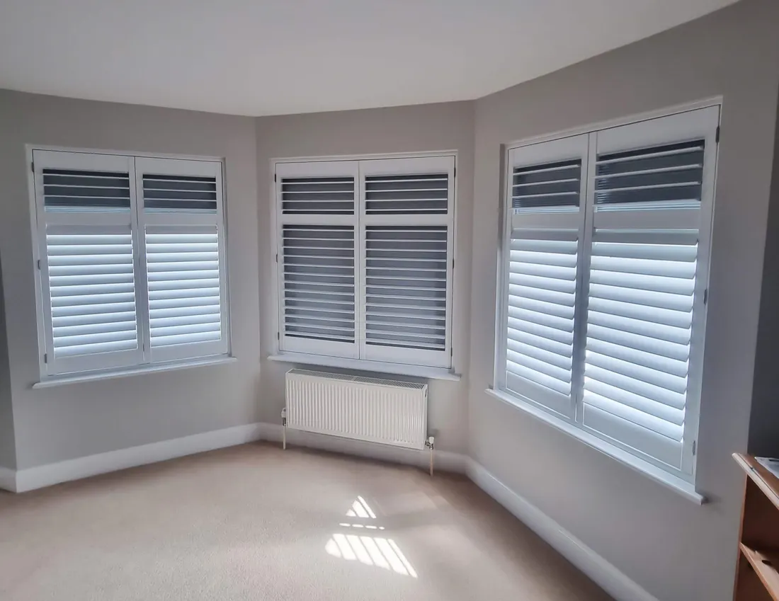 Grey blackout shutters on the windows of a bay in a bedroom