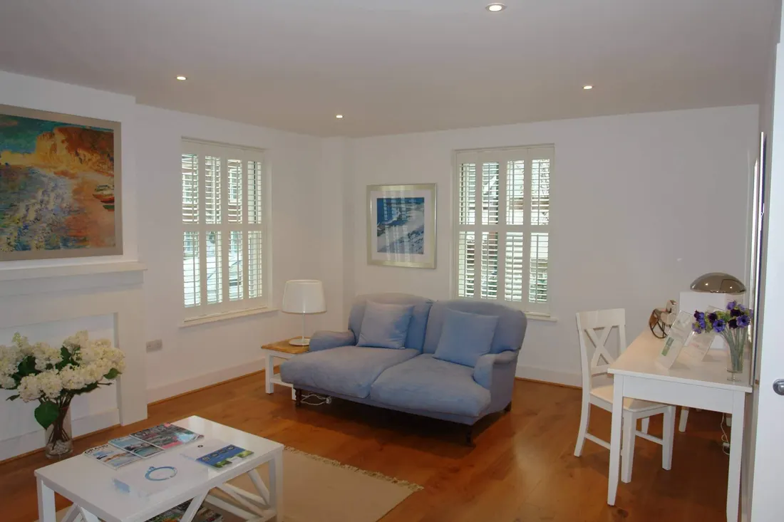 Full-height shutters behind a sofa in a sitting room