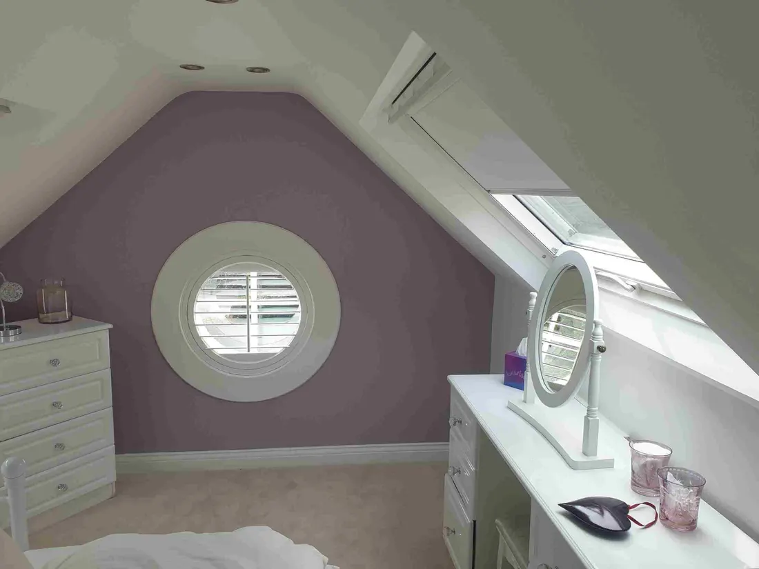 A round shutter on a porthole window in an attic bedroom