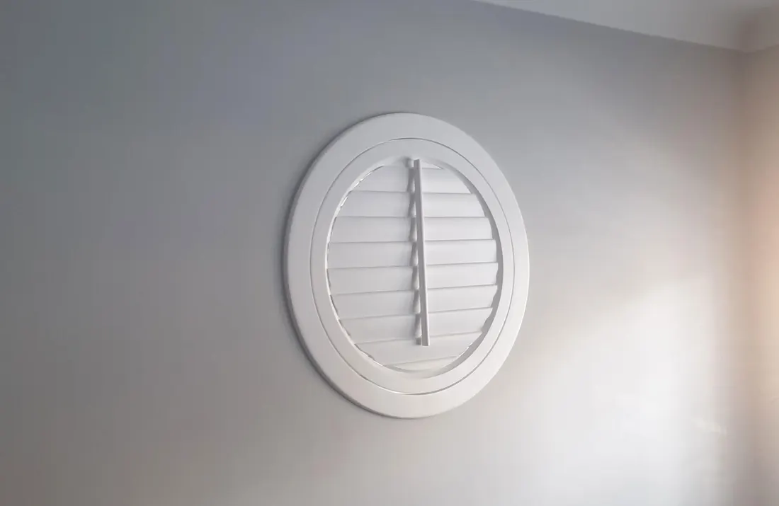 A closed round white shutter on a circular window