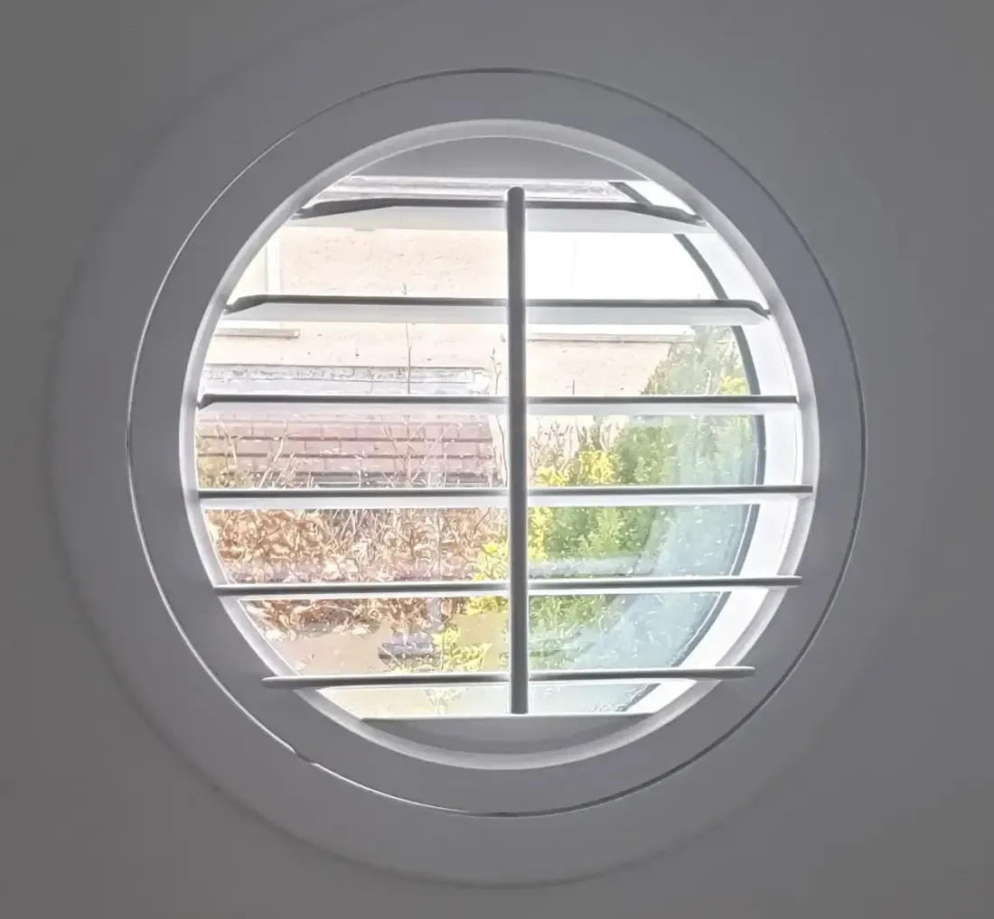 A round shutter with its split panels open to a garden