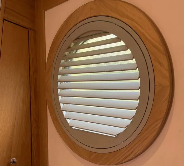 A round white shutter set inside a timber porthole frame