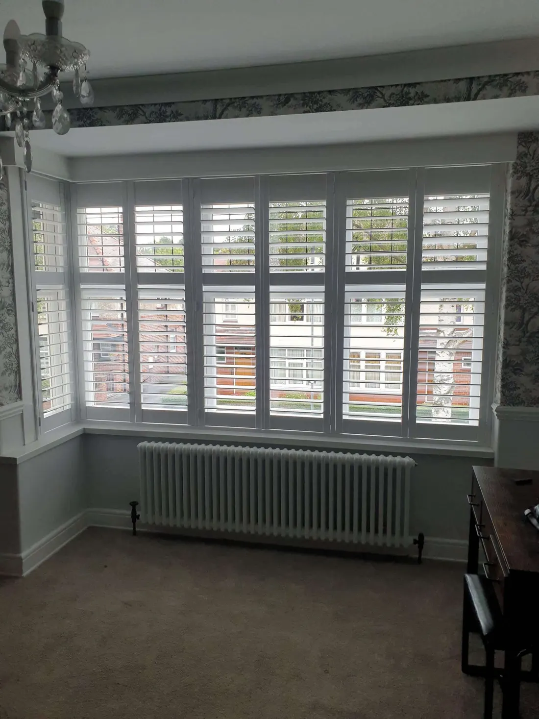 White shutters fitted to all three faces of a square bay in a front room