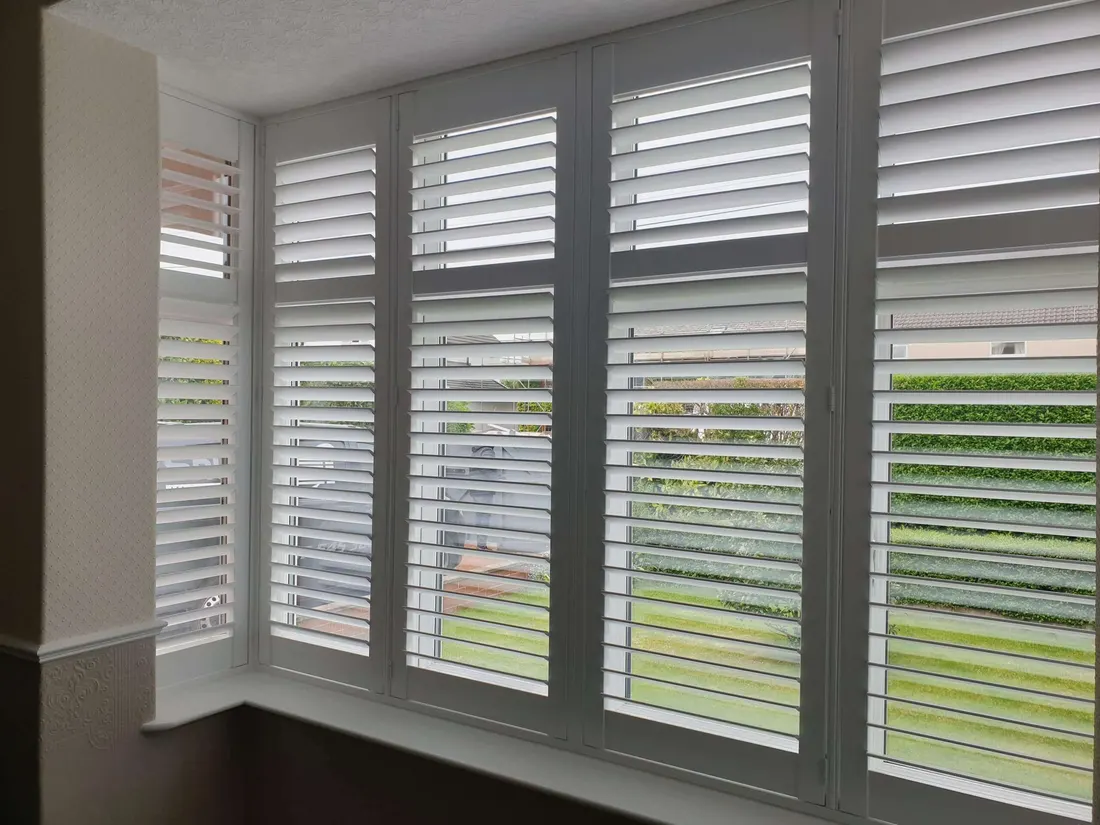 Square bay shutters with the louvres tilted open onto the street